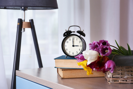 Alarm clock with tulips bouquet on tableの写真素材