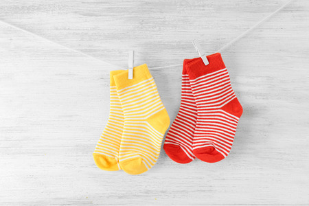 Baby socks hanging on the clothesline on wooden background