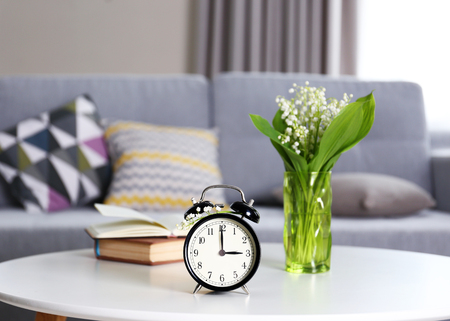 Alarm clock with lily bouquet on table
