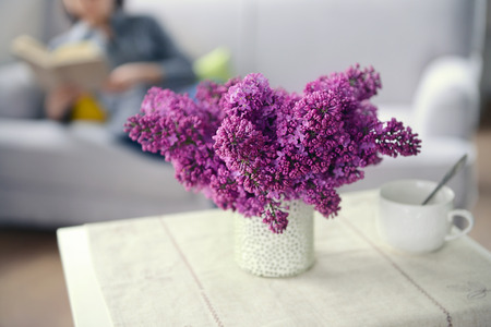 Lilac bouquet in ceramic jar on white table