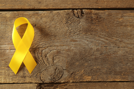 Yellow awareness ribbon on wooden backgroundの写真素材
