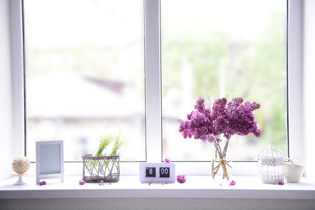 Lilac bouquet in glass jar and may-lilies on windowsillの写真素材
