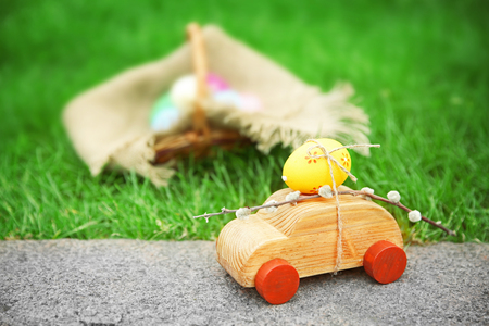Decorative toy car with pussy willow and Easter egg on green grass backgroundの写真素材