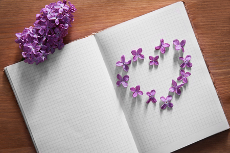Lilac flowers in a heart shape on open white bookの写真素材