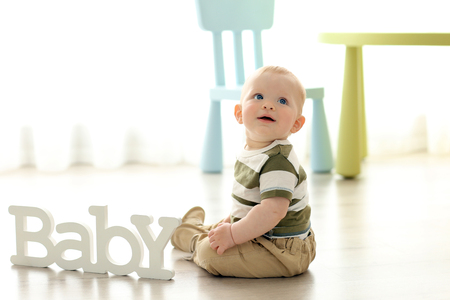 Baby sitting on a wooden floorの写真素材