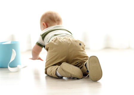 Adorable crawling baby on a wooden floorの写真素材