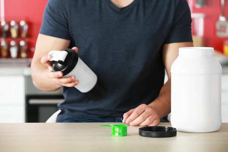 Young man making healthy cocktail in kitchenの写真素材