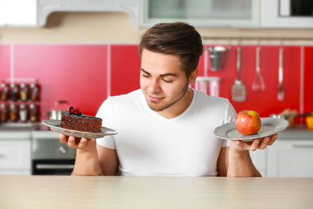 Man with healthy and unhealthy food in kitchenの写真素材