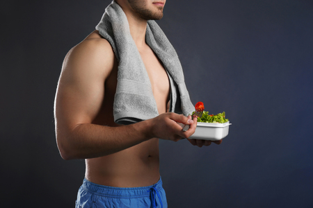 Young man with healthy food on dark backgroundの写真素材