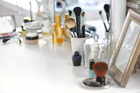 Cosmetic brushes in cup on light dressing tableの写真素材
