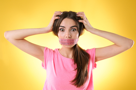 Woman with locked mouth for diet on yellow backgroundの写真素材