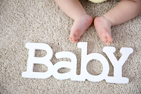 Baby legs and decorative word on the floorの写真素材