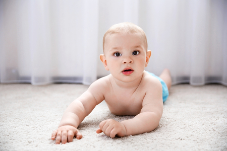 Baby boy on the floor beside windowの写真素材