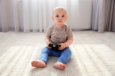 Baby boy playing with old camera on the floor