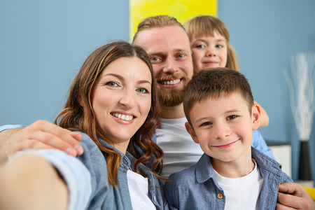 Happy family taking selfie on blue wall backgroundの写真素材