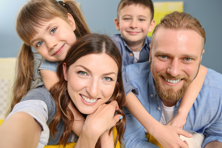 Happy family taking selfie on blue wall background