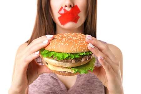 Woman with tied mouth holding hamburger isolated on whiteの写真素材