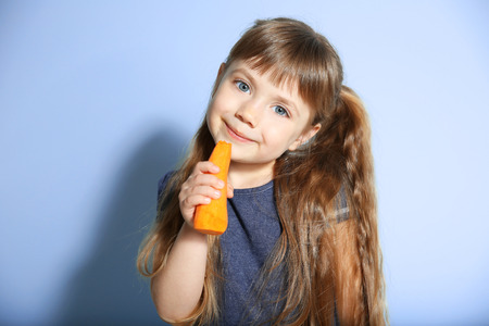 Little girl with carrot on wall backgroundの写真素材