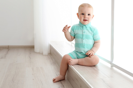 Baby boy sitting on the window indoorsの写真素材