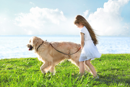 Little girl and big kind dog on the riversideの写真素材
