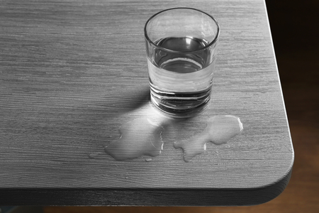 Glass of water spilled on wooden tableの写真素材