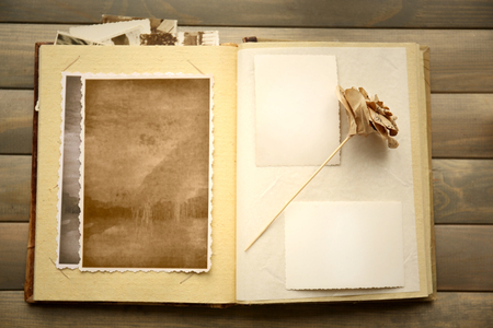 Album with vintage photos and decorative paper rose on wooden backgroundの写真素材