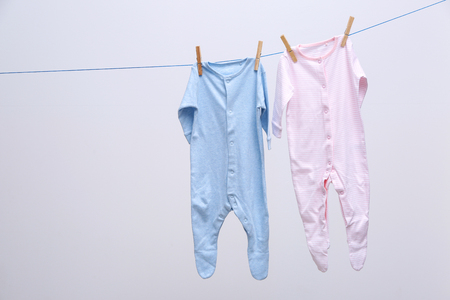 Baby clothes hanging on rope, isolated on whiteの写真素材