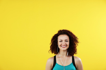 Attractive woman listening to music with headphones on yellow backgroundの写真素材