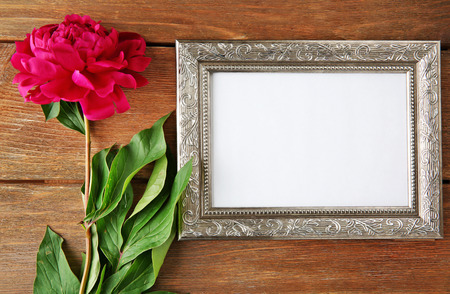 Beautiful peony and empty frame on wooden backgroundの写真素材