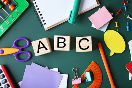Composition of colourful stationery and word ABC on chalkboard