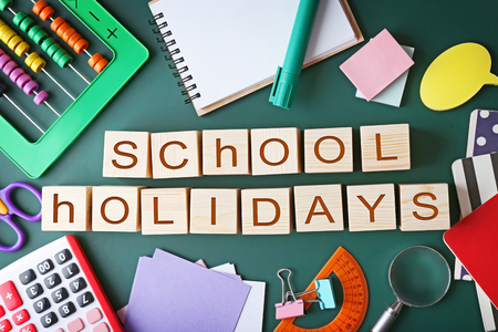 Colourful stationery and words SCHOOL HOLIDAYS on chalkboardの写真素材