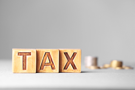 Tax concept with wooden cubes and coins on grey backgroundの写真素材