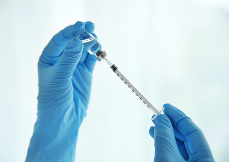 Doctor hands with syringe on light backgroundの写真素材