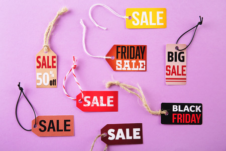 Paper tags with strings and word sale on pink background