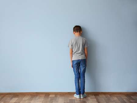 Family problems concept. Punished boy standing near wallの写真素材