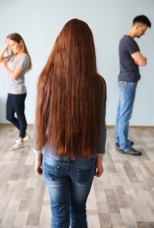 Family problems concept. Girl looking on abusing parentsの写真素材