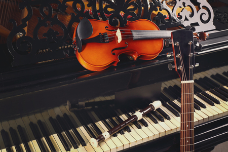 Flute, violin and guitar neck on pianoの写真素材