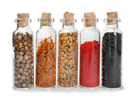 Assorted dry spices in glass bottles on white backgroundの写真素材