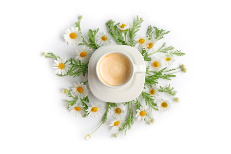 Cup of coffee with fresh flowers lying around on white backgroundの写真素材