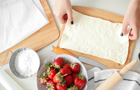 Female hands cooking strawberry dessert in kitchenの写真素材