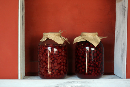 Preserved cherries in glass jar on white wooden shelfの写真素材