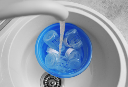 Sterilizing baby bottles in plastic blue basinの写真素材