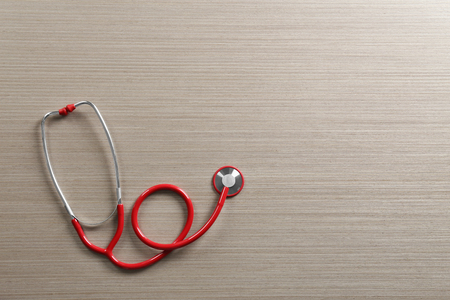Red stethoscope on wooden tableの写真素材