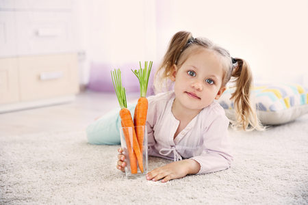 Beautiful girl with carrots at homeの写真素材