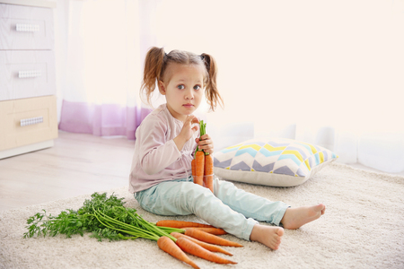 Beautiful girl with carrots at homeの写真素材