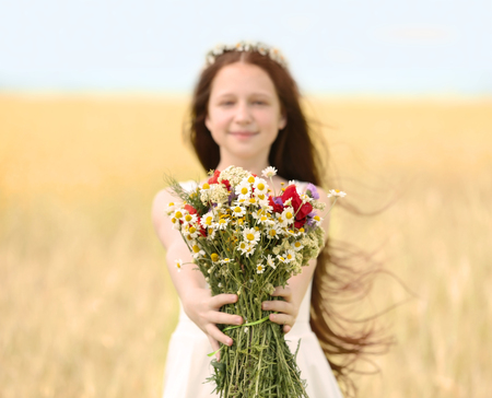 Portrait of girl in meadow with wild spring flowers bouquetの写真素材