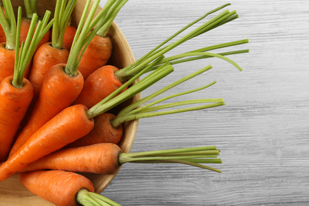 Fresh carrots in a bowl on wooden backgroundの写真素材