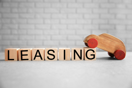 Cubes with word LEASING and toy car on brick wall backgroundの写真素材