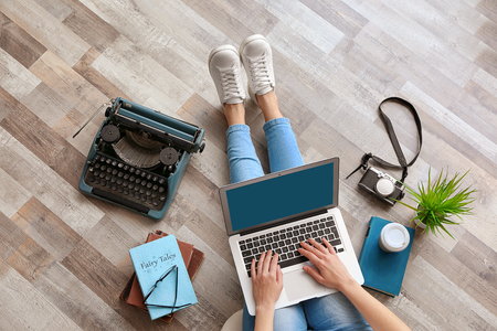 Woman working with laptop on wooden floorの写真素材