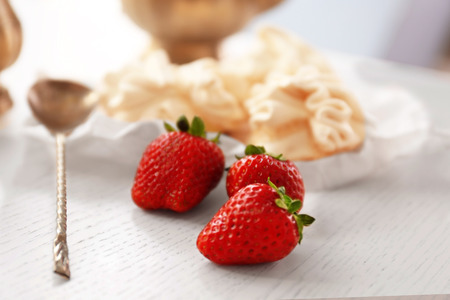 Strawberries and spoon on wooden tableの写真素材